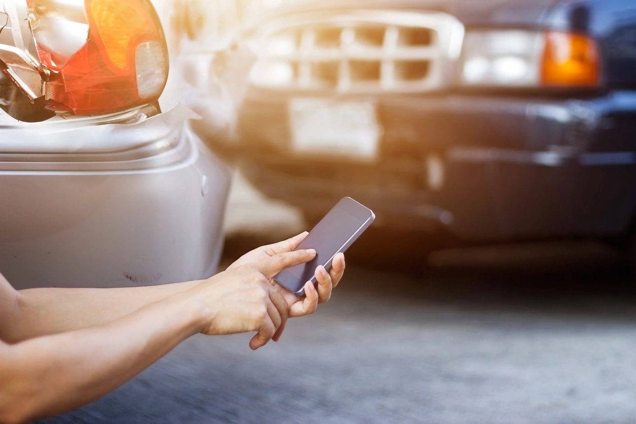 A person holding their cell phone in front of a car.