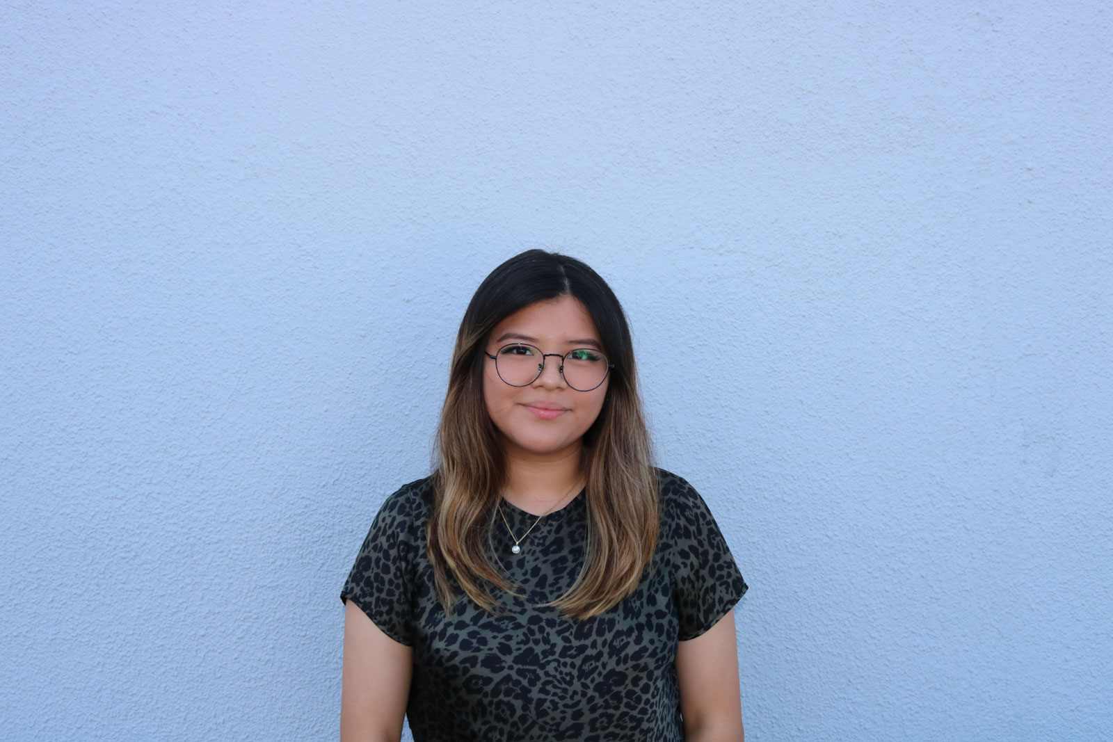 A woman standing in front of a blue wall.