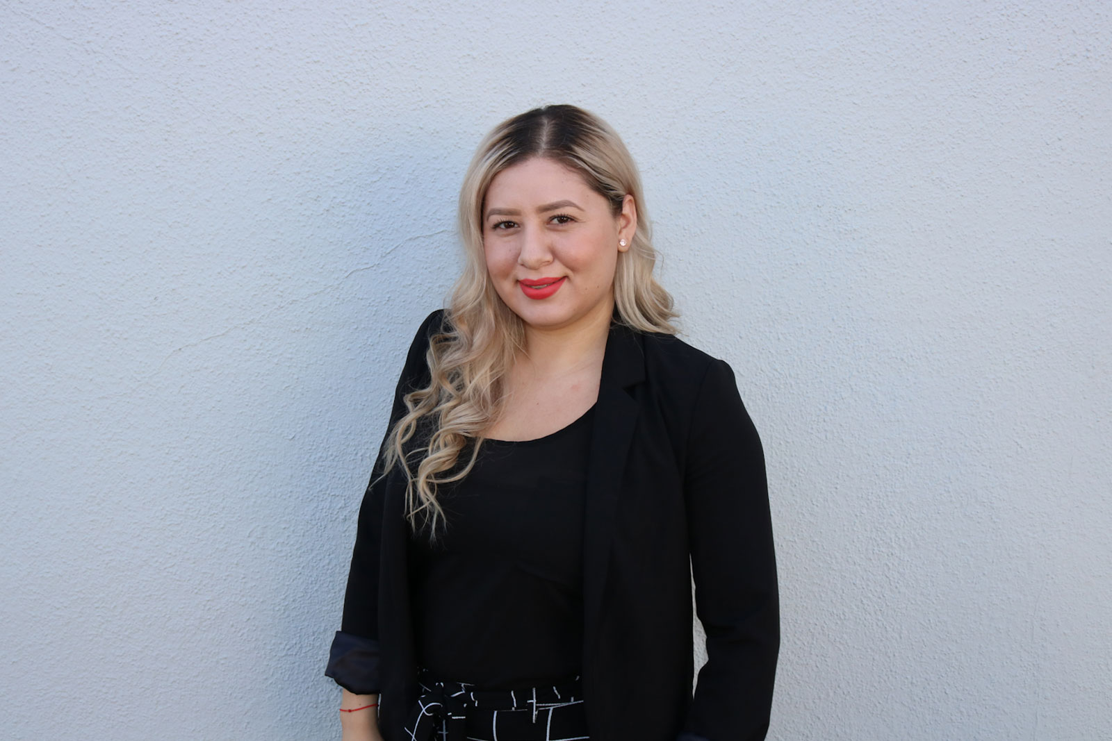 A woman standing in front of a white wall.